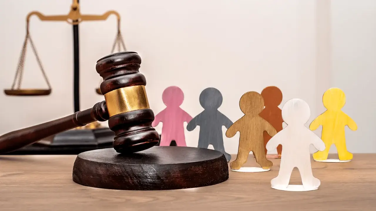Marteau de juge, balance de la justice et figurines représentant des personnes. Un locataire à éviter peut entraîner des litiges.