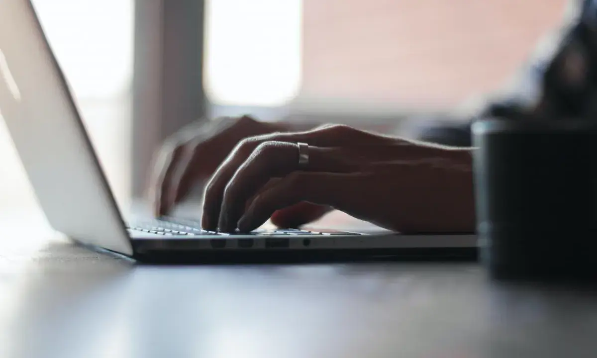 Mains tapant sur un ordinateur portable, recherchant comment déclarer une location meublée à l'année.