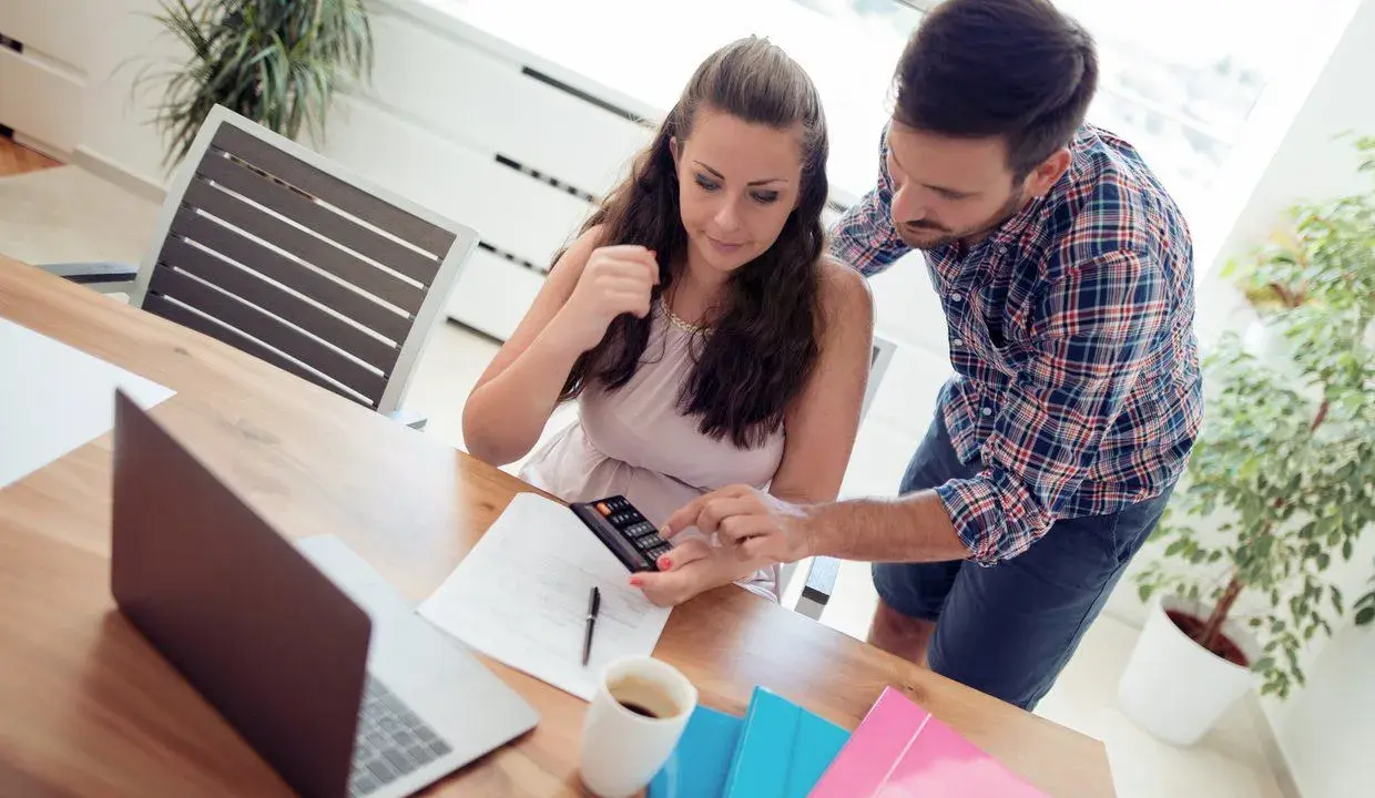 Couple calculant comment déduire la CSG déductible des impôts, avec calculatrice et documents sur la table.
