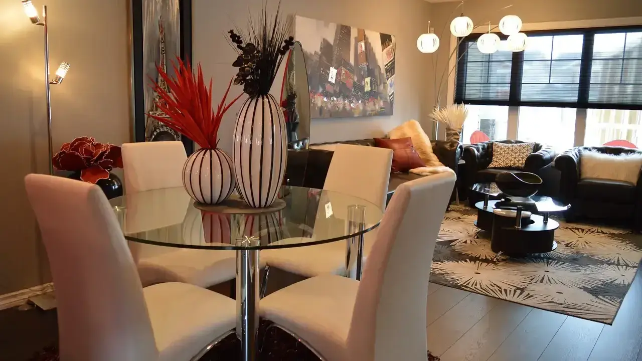 Table à manger moderne avec chaises blanches, parfaite pour une lmnp residence secondaire. Salon cosy avec canapés en cuir et tapis graphique.