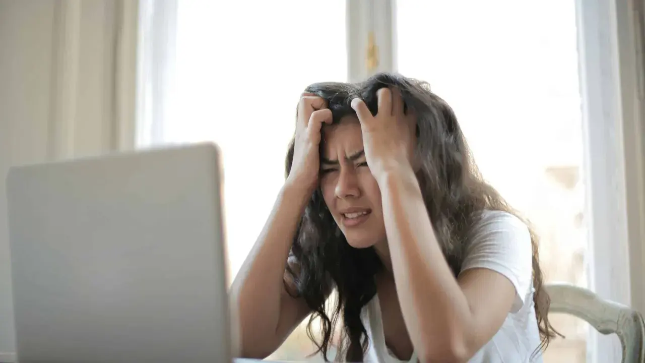 Jeune femme stressée devant son ordinateur, confrontée à la complexité de la réglementation d'une location saisonnière.