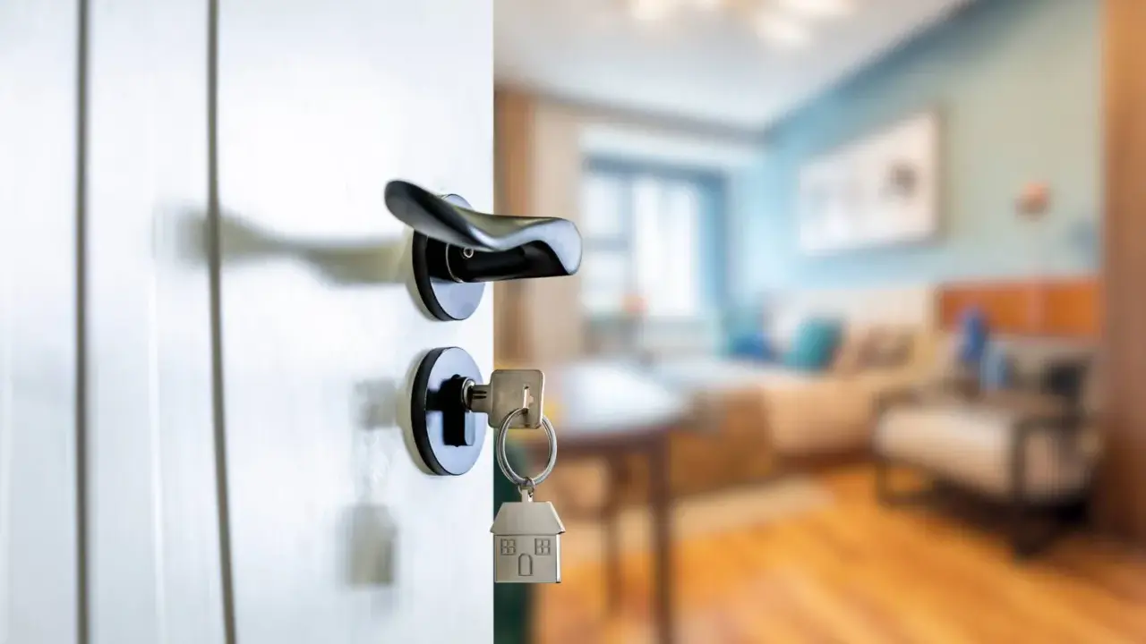 Clé sur la serrure d'une porte ouverte sur un salon. Le locataire peut exercer son droit de préemption si le prix baisse.