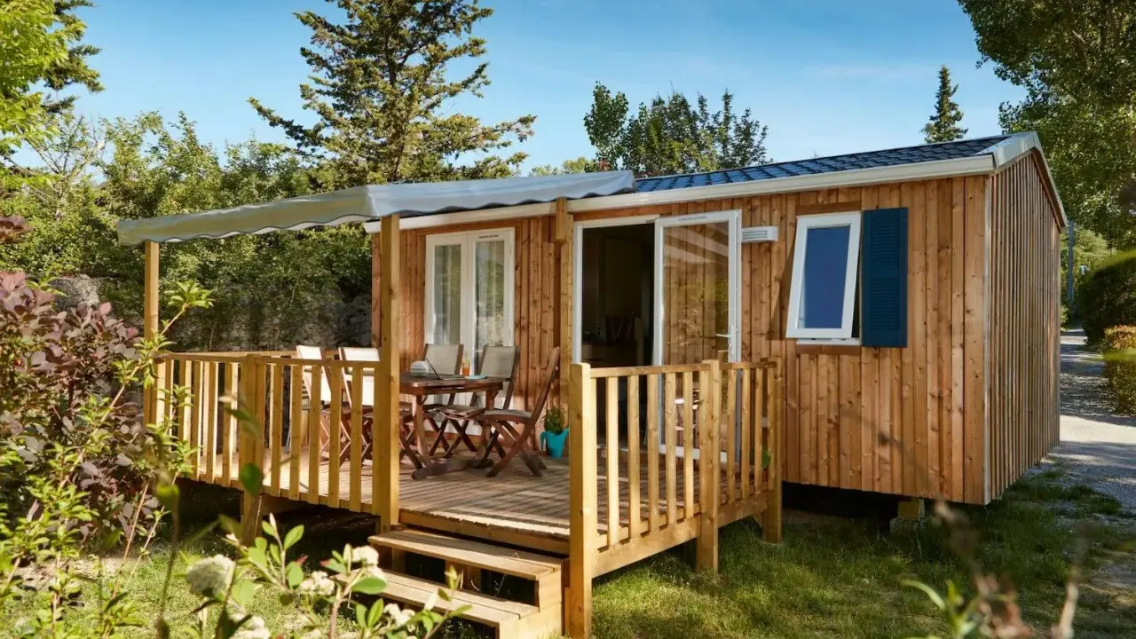 Mobil-home en bois avec terrasse, table et chaises. Découvrez quelle condition pour mettre un mobil-home sur son terrain.