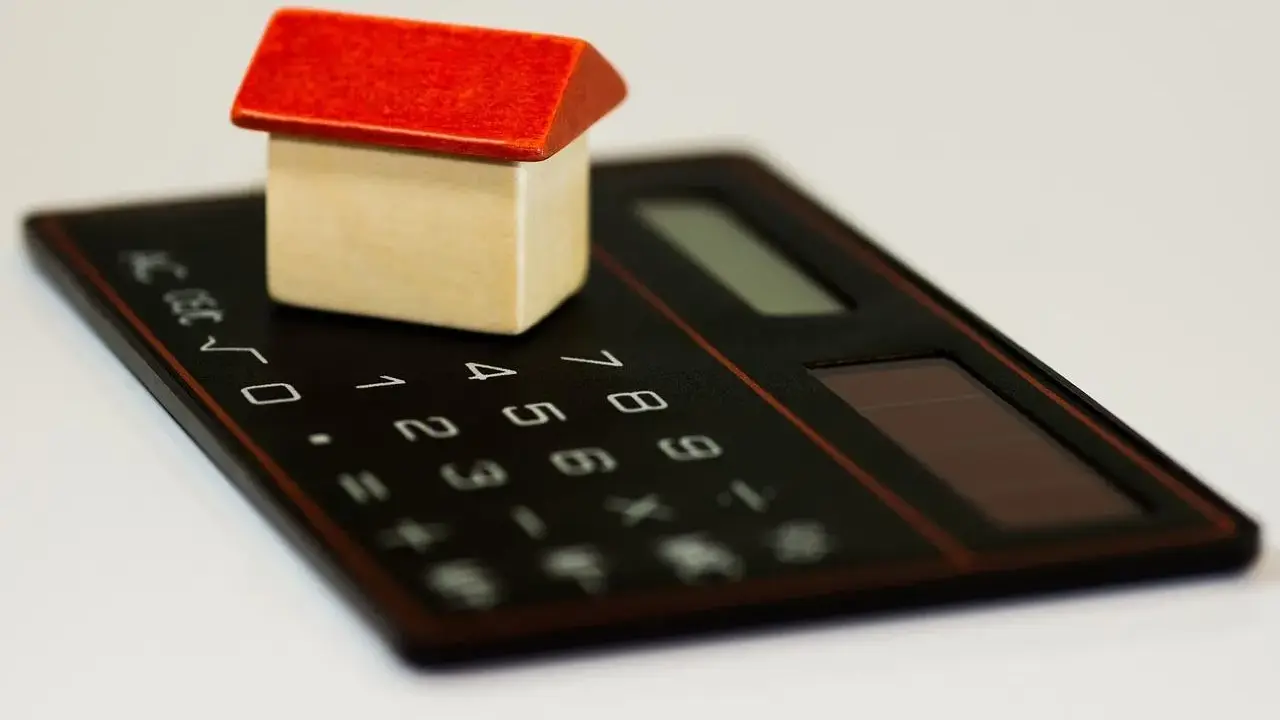 Maisonnette en bois sur calculatrice, symbolisant la régularisation de charges locatives tardives.