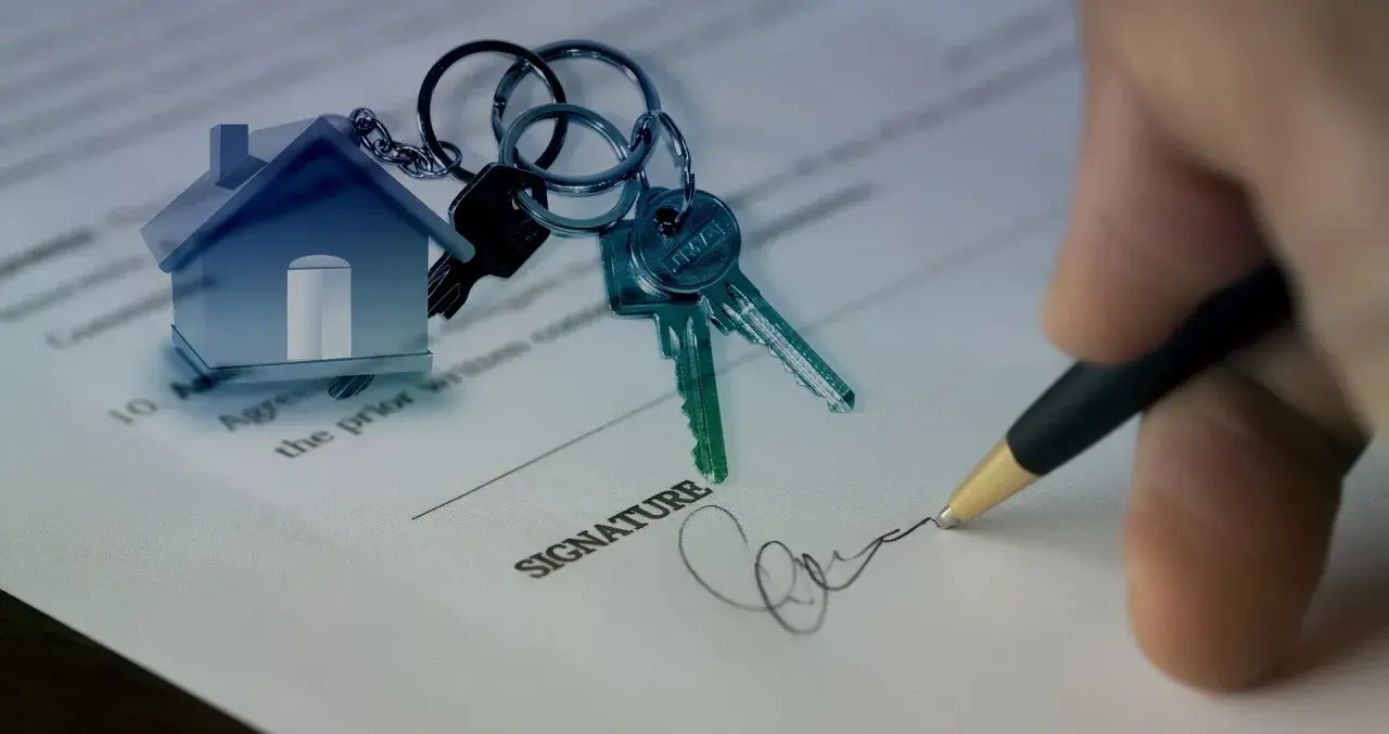 Clés d'une maison sur un contrat, symbolisant un prêt consommation pour achat immobilier. Signature apposée.