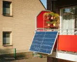 Panneau solaire sur un balcon rouge, peut-être pour contester une augmentation de loyer liée au DPE.