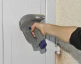 Main tenant une sonde pour vérifier la présence de peinture au plomb sur une porte.