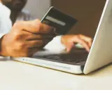 Homme utilisant une carte bancaire sur un ordinateur portable pour configurer un virement automatique de loyer avec son RIB.