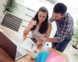Couple calculant comment déduire la CSG déductible des impôts, avec calculatrice et documents sur la table.