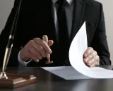 Un homme en costume appose un sceau sur un document, étape clé pour savoir comment obtenir un titre de propriété.