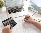 Calculatrice, ordinateur et formulaires fiscaux. On y voit des calculs pour déterminer quels sont les intérêts d'emprunt déductibles.