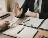 Un homme en costume refuse de l'argent, peut-être pour éviter des refus de banque pour annuler un compromis.