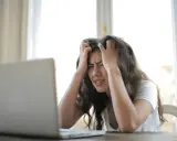 Jeune femme stressée devant son ordinateur, confrontée à la complexité de la réglementation d'une location saisonnière.