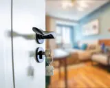 Clé sur la serrure d'une porte ouverte sur un salon. Le locataire peut exercer son droit de préemption si le prix baisse.