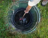 Vidange fosse septique avant le départ du locataire. Un homme utilise un outil pour nettoyer le fond de la fosse.