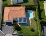 Vue aérienne d'une maison avec piscine et véranda. Une dépendance maison impôts, un garage et une allée complètent le paysage.