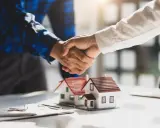 Poignée de main sur des maquettes de maisons, symbolisant un accord. Le compromis de vente délai dépassé par le vendeur est une préoccupation.