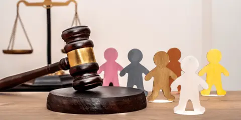 Marteau de juge, balance de la justice et figurines représentant des personnes. Un locataire à éviter peut entraîner des litiges.