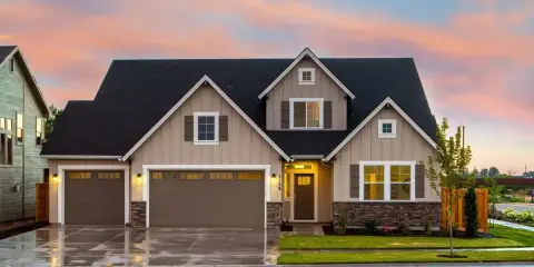 Belle maison avec garage double sous un ciel de crépuscule. Une image parfaite pour illustrer la condition pour acheter une maison.