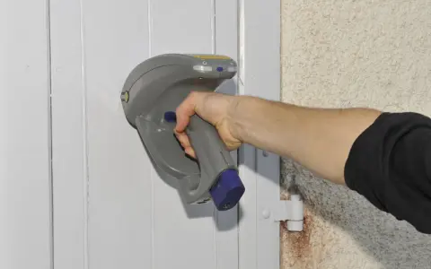 Main tenant une sonde pour vérifier la présence de peinture au plomb sur une porte.
