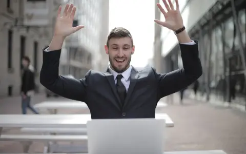 Homme en costume, bras levés, devant un ordinateur. Il semble avoir trouvé quel salaire pour emprunter 400 000 euros.