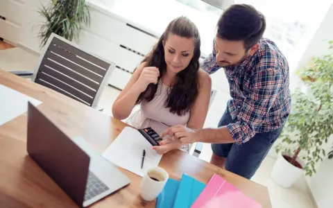Couple calculant comment déduire la CSG déductible des impôts, avec calculatrice et documents sur la table.