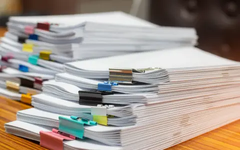 Piles de documents, certains reliés par des pinces colorées, prêts pour le service de la publicité foncière.