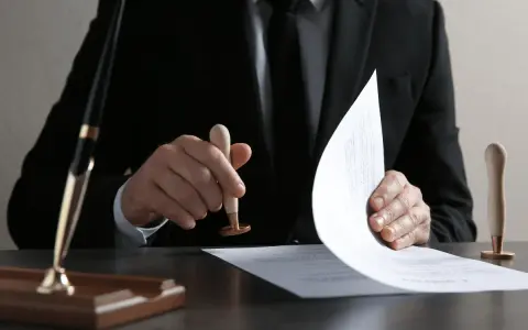 Un homme en costume appose un sceau sur un document, étape clé pour savoir comment obtenir un titre de propriété.