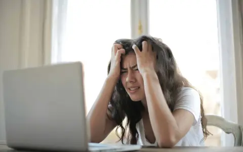 Jeune femme stressée devant son ordinateur, confrontée à la complexité de la réglementation d'une location saisonnière.