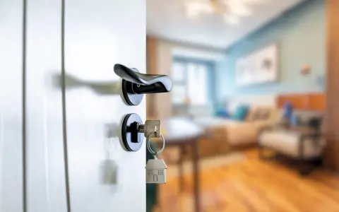 Clé sur la serrure d'une porte ouverte sur un salon. Le locataire peut exercer son droit de préemption si le prix baisse.