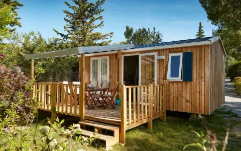 Mobil-home en bois avec terrasse, table et chaises. Découvrez quelle condition pour mettre un mobil-home sur son terrain.