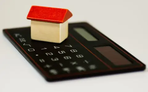 Maisonnette en bois sur calculatrice, symbolisant la régularisation de charges locatives tardives.