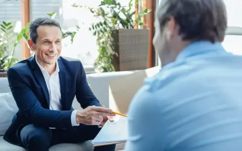 Un homme souriant en costume explique un document, discutant du délai de l'offre de prêt.