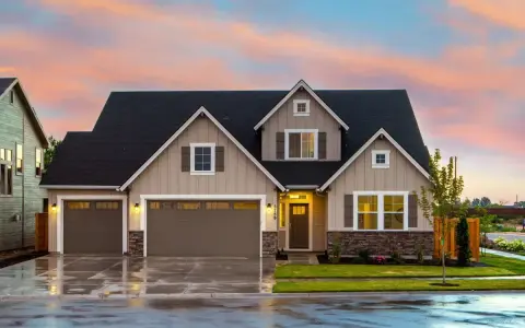 Belle maison avec garage double sous un ciel de crépuscule. Une image parfaite pour illustrer la condition pour acheter une maison.