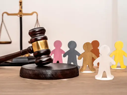Marteau de juge, balance de la justice et figurines représentant des personnes. Un locataire à éviter peut entraîner des litiges.
