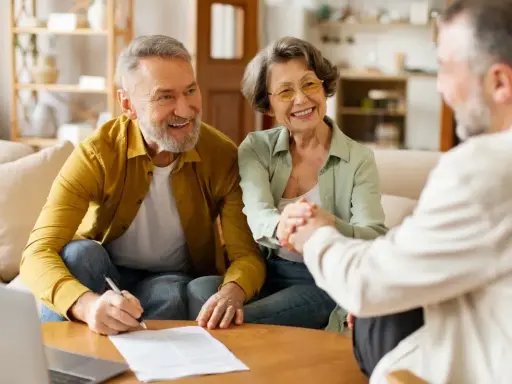 Couple âgé souriant discutant avec un conseiller, signature d'un prêt relais senior.