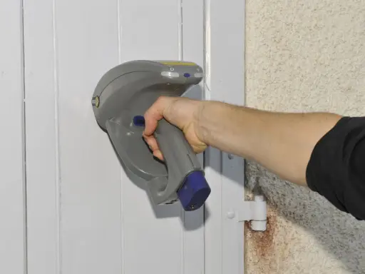 Main tenant une sonde pour vérifier la présence de peinture au plomb sur une porte.