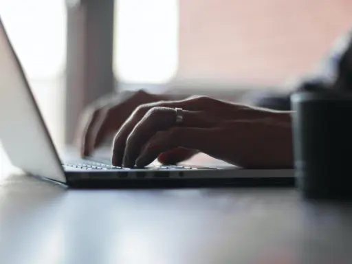 Mains tapant sur un ordinateur portable, recherchant comment déclarer une location meublée à l'année.