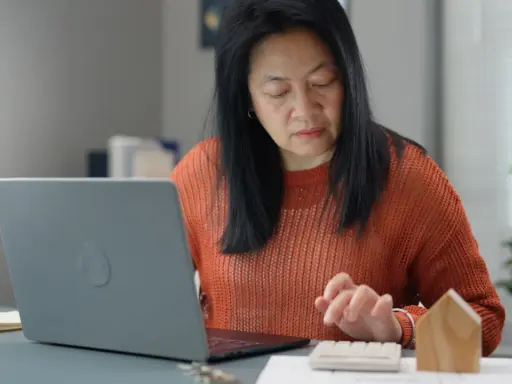 Femme calculant des frais de location avec un ordinateur portable et une calculatrice.