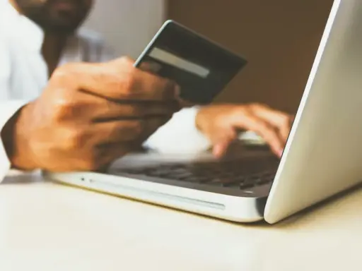 Homme utilisant une carte bancaire sur un ordinateur portable pour configurer un virement automatique de loyer avec son RIB.