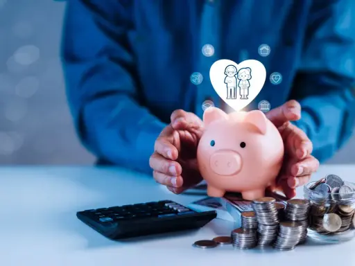 Une tirelire rose protège un cœur avec un couple âgé, symbolisant le prêt familial : les erreurs à ne pas commettre. Calculatrice et pièces à proximité.