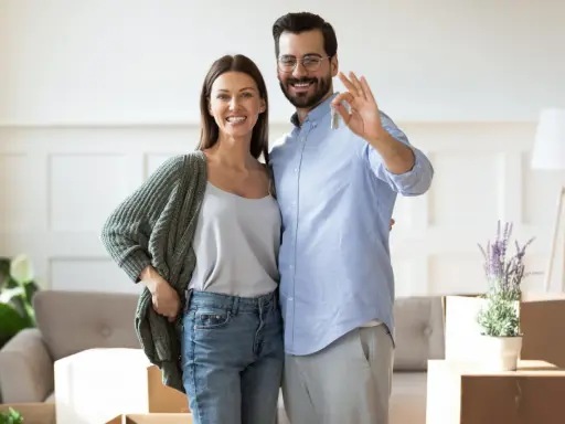 Couple heureux tenant les clés de leur nouvelle maison. L'homme fait le signe OK, symbolisant la réussite de leur projet immobilier, sans annulation offre d'achat par l'acheteur.