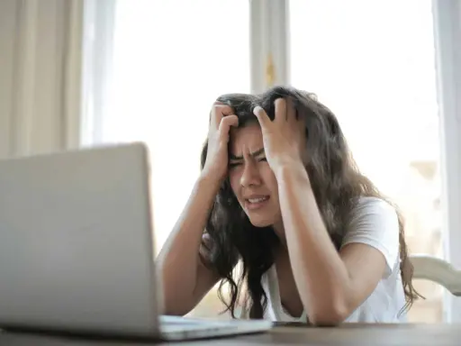 Jeune femme stressée devant son ordinateur, confrontée à la complexité de la réglementation d'une location saisonnière.