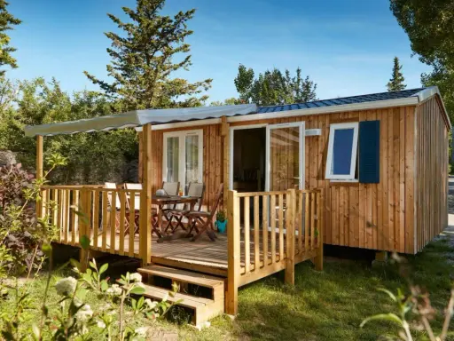 Mobil-home en bois avec terrasse, table et chaises. Découvrez quelle condition pour mettre un mobil-home sur son terrain.