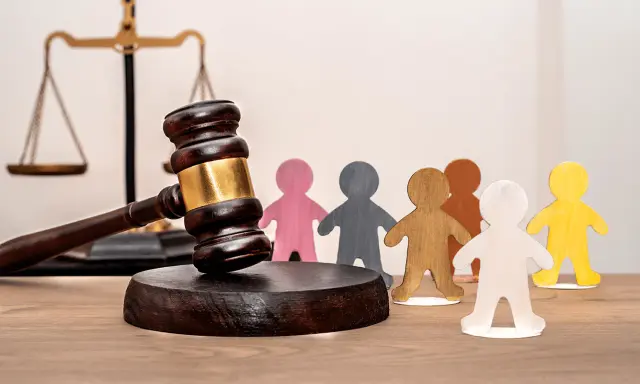 Marteau de juge, balance de la justice et figurines représentant des personnes. Un locataire à éviter peut entraîner des litiges.