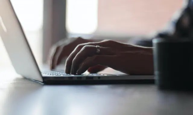 Mains tapant sur un ordinateur portable, recherchant comment déclarer une location meublée à l'année.