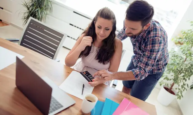 Couple calculant comment déduire la CSG déductible des impôts, avec calculatrice et documents sur la table.