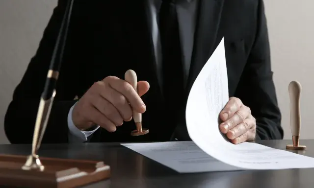Un homme en costume appose un sceau sur un document, étape clé pour savoir comment obtenir un titre de propriété.