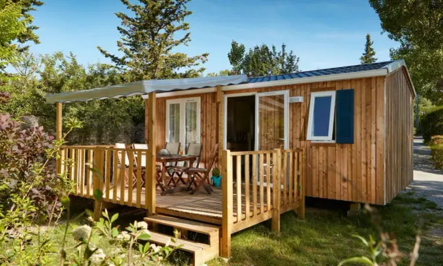Mobil-home en bois avec terrasse, table et chaises. Découvrez quelle condition pour mettre un mobil-home sur son terrain.
