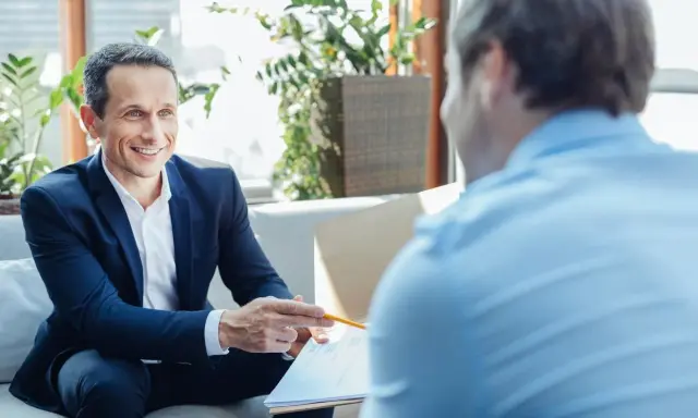Un homme souriant en costume explique un document, discutant du délai de l'offre de prêt.